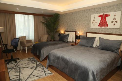 a hotel room with two beds and a dress on the wall at Cebeci Grand Hotel in Trabzon