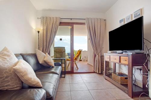a living room with a couch and a flat screen tv at Casa Rosa in Costa Teguise