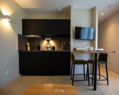 a kitchen with black cabinets and a table with chairs at La Maison du Gindreau in Saint-Médard