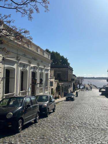 two cars parked in front of a building on a cobblestone street at Casa Lahusen in Colonia del Sacramento