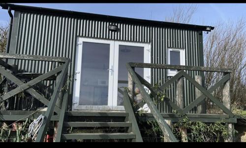 a small house with a white door and stairs at Shepherds hut in 7 acre field in Ludworth
