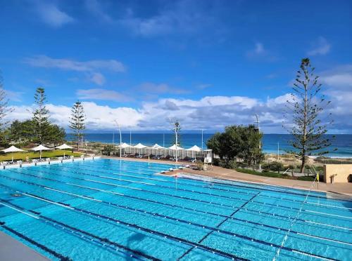 a large swimming pool with the ocean in the background at Modern King Suite on Swan Valley Doorstep in West Swan