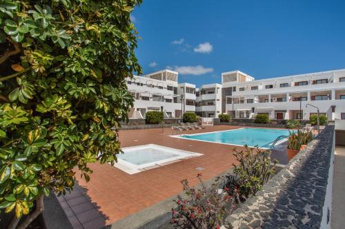 an apartment with a swimming pool and a building at Casa Rosa in Costa Teguise