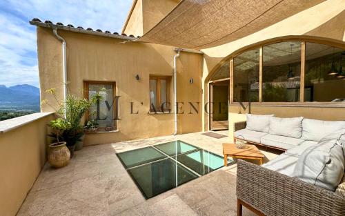 une terrasse avec un canapé et une table en verre dans l'établissement Casa Louisa Typique & piscine LUMIO, à Lumio