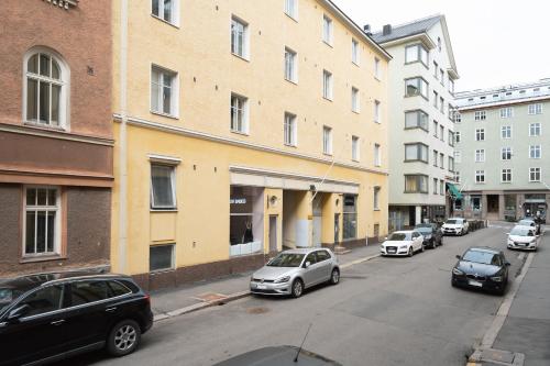 a street with cars parked in front of a building at Modern & Renovated 1BR Apt in City Center in Helsinki