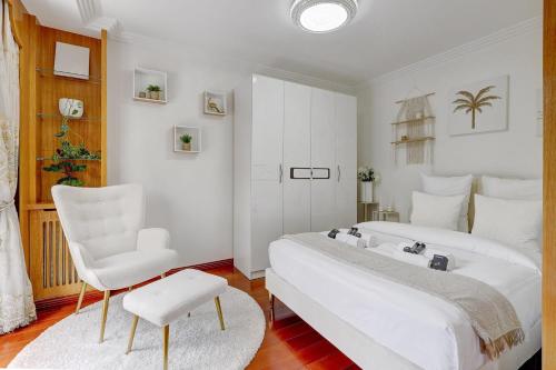 une chambre blanche avec deux lits et une chaise dans l'établissement L'ideal Luxe et Terrasse pres de Republique, à Paris