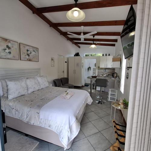 a bedroom with a white bed and a kitchen at Sleep Haven Self-Catering Accommodation - Nelspruit in Nelspruit
