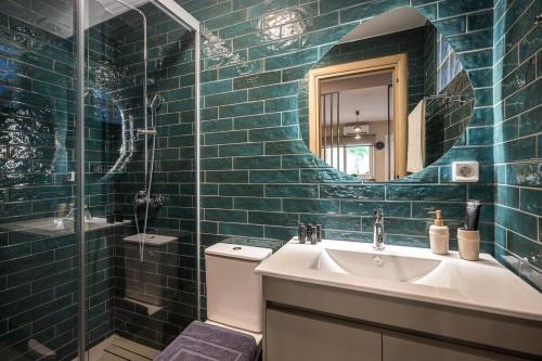 a blue tiled bathroom with a sink and a mirror at Herophile apartment close to airport & city center in Néa Alikarnassós