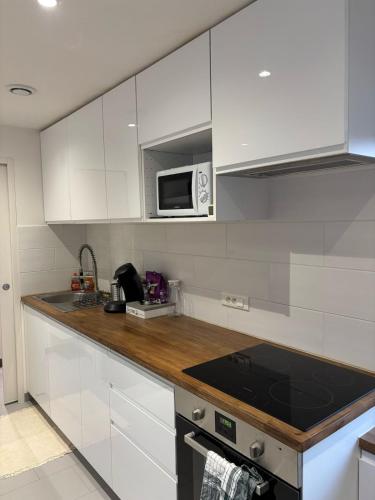 une cuisine avec des armoires blanches et un four à plaques de cuisson dans l'établissement Appartement neuf CDG, Asterix, Chantilly, Mer de Sable, à La Chapelle-en-Serval
