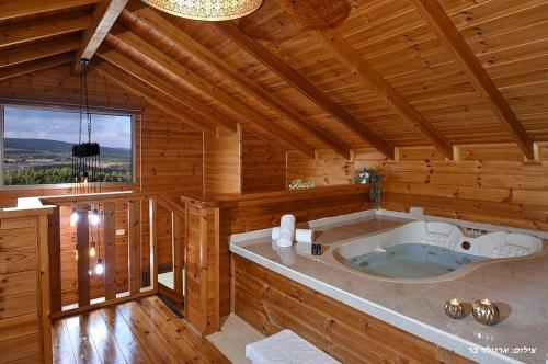 a large tub in a wooden room with a window at בקתה בשמורה in Shomera