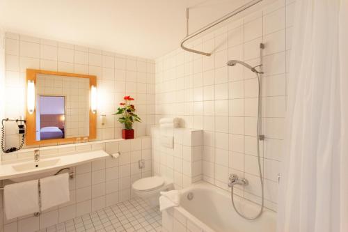 a bathroom with a tub and a toilet and a sink at Saar City Hotel in Saarbrücken