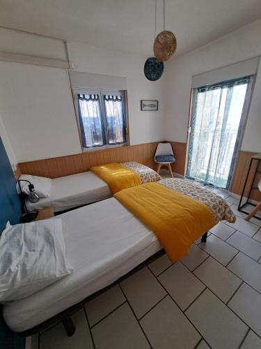 - une chambre avec 2 lits avec des draps jaunes dans l'établissement Appartement Calme et idéalement situé, à Port-Vendres