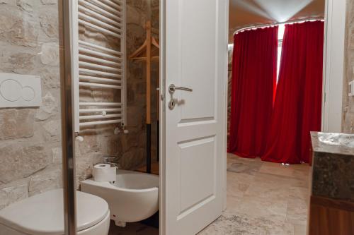 a bathroom with a toilet and a red curtain at La Trinità Private Spa in Corciano
