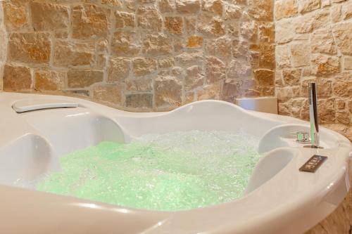 a bath tub filled with green water in a bathroom at La Trinità Private Spa in Corciano