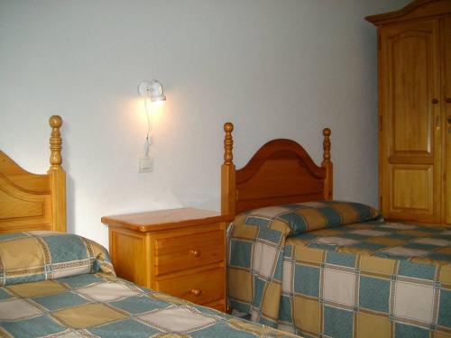 sypialnia z 2 łóżkami, komodą i spódnicą w obiekcie Alojamiento CR Cuatro Caminos w mieście San Pablo de los Montes