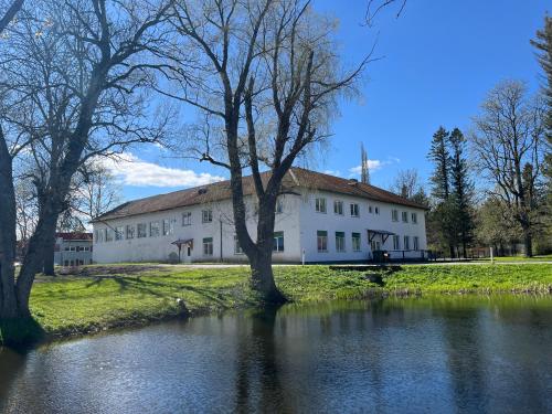 a large white building next to a river at Raasiku majutus in Raasiku