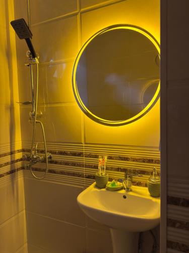 Baño amarillo con lavabo y espejo en Hotel Sataplia, en Banoja