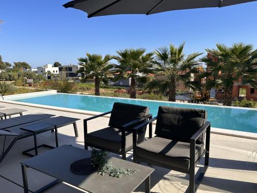 a patio with tables and chairs and a swimming pool at Luxury TABOO Villa & Spa in Medulin for 8 people with heated pool- wellness & sea view in Medulin