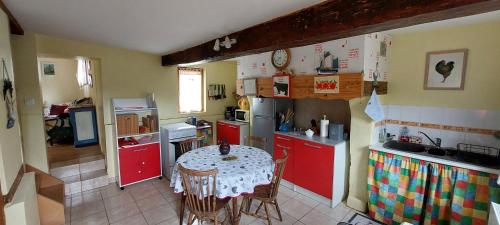 une petite cuisine avec une table et des placards rouges dans l'établissement Gîte de charme au coeur du Marais-Vernier, à Marais-Vernier
