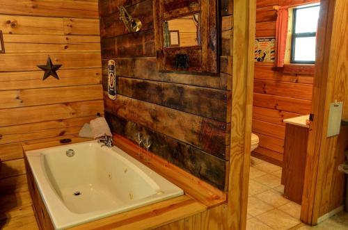 ein Holzbadezimmer mit einer Badewanne und einem Spiegel in der Unterkunft Secluded Log Cabin for a Romantic Getaway near Maggie Valley, North Carolina in Cherokee