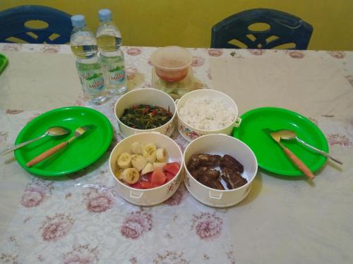 a table with four bowls of food and green plates at Amaro Homestay in Nuhu Tawun