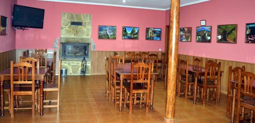 a dining room with tables and chairs and a fireplace at Albergue Aurora Boreal in Casas del Monte