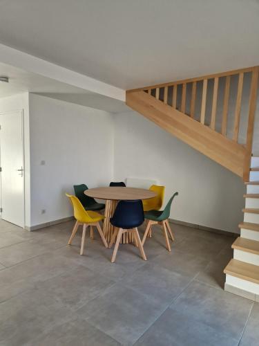 une table et des chaises dans une pièce avec un escalier dans l'établissement Charmante maison de village, à Choisey