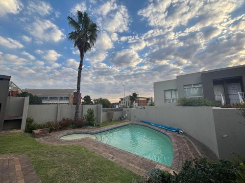 a swimming pool in the backyard of a house with a palm tree at Durbanville Self Catering Apartments in Cape Town