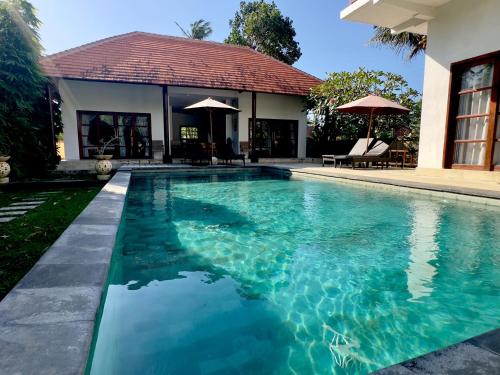 a swimming pool in front of a house at Villa Light - Amed Bali in Amed