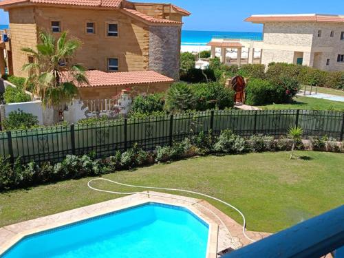 a swimming pool in a yard next to a house at استمتع بالصيف في فيلا الأحلام مكيفة بالكامل وبخطوات من البحر in Dawwār Ibrāhīm Abū Shunaywīr