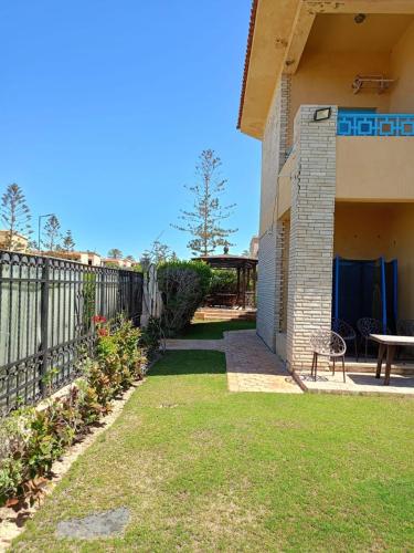 a backyard of a house with a table and a fence at استمتع بالصيف في فيلا الأحلام مكيفة بالكامل وبخطوات من البحر in Dawwār Ibrāhīm Abū Shunaywīr