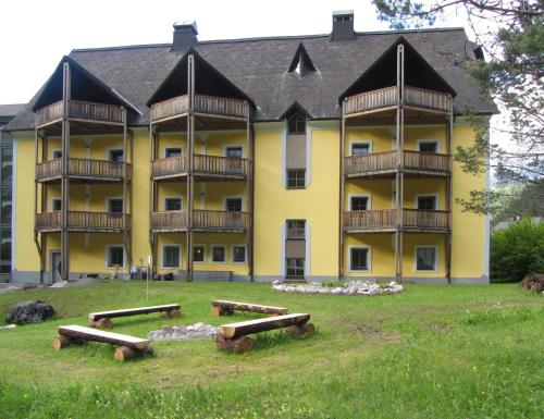 a large yellow building with benches in front of it at Hotel Bergkristall in Wildalpen