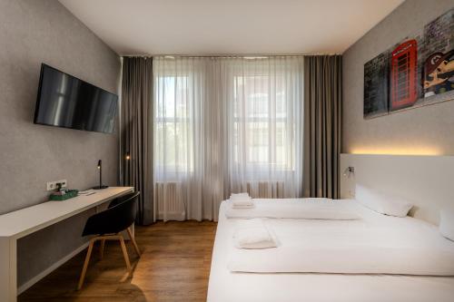 a hotel room with two beds and a desk at mk hotel berlin in Berlin