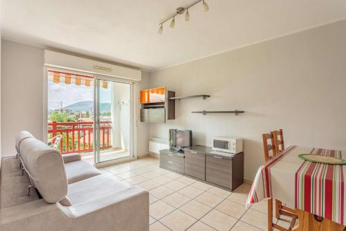 Il comprend un salon avec une table et une cuisine équipée d'un four micro-ondes. dans l'établissement Biantenia B23 Appartement avec balcon et parking sur les hauteurs, à Hendaye