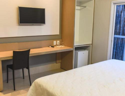 a bedroom with a desk and a bed and a television at Hotel D'Leon in Gurupi