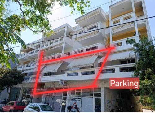 a large white building with a red sign in front of it at Daphne's apartment in Kavala