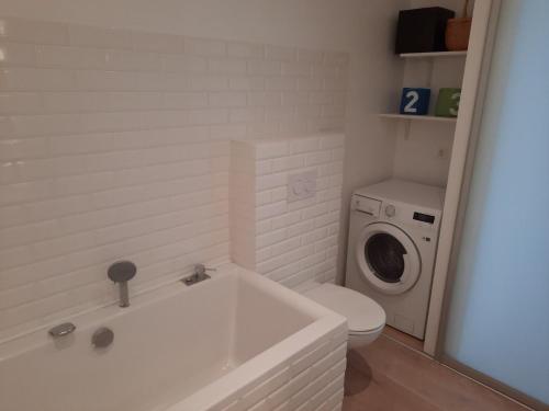 a bathroom with a white tub and a washing machine at Forest view apartment in Melnragė