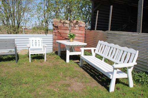 two white benches and a table with a potted plant at Apartment Gasstorp Wifi in Hova