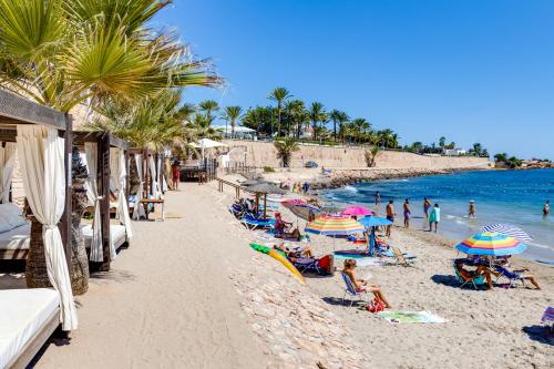 a beach with people sitting on chairs and umbrellas at Descanso en la Costa in Dehesa de Campoamor