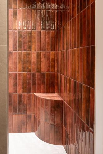 a shower with brown tiled walls and a wooden shelf at TatryTop Słoneczna Rezydencja Jacuzzi & Sauna in Białka Tatrzanska