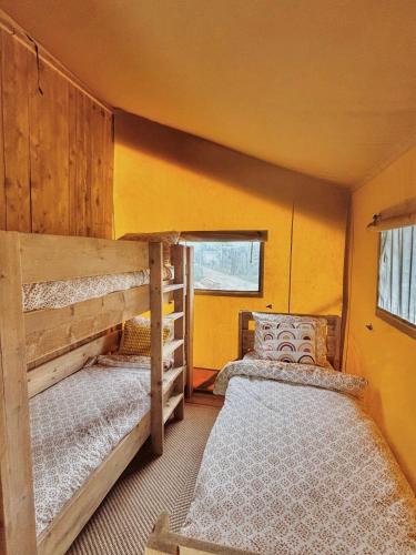 two bunk beds in a room with yellow walls at Glampingtent Grou in Grou