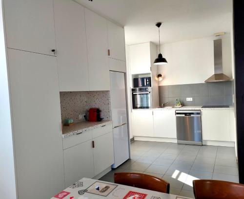 une cuisine avec des armoires blanches et une table et des chaises dans l'établissement Large apartment parking, à Epfig