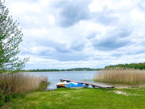 a boat is parked next to a dock on a lake at Glamping w sercu mazur z prywatną plażą in Regiel