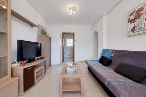 a living room with a couch and a flat screen tv at Descanso en la Costa in Dehesa de Campoamor