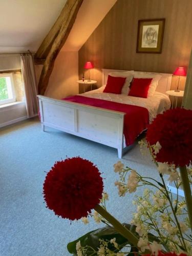 a bedroom with a bed with red pillows and flowers at Domaine la Cabane in Dégagnac