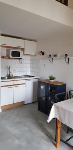 - une cuisine avec des placards blancs, un évier et une table dans l'établissement Duplex climatisé à 50 mètres de la plage des Lecques, à Saint-Cyr-sur-Mer