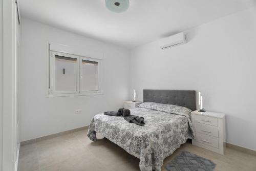 a white bedroom with a bed and a dresser and window at Villa Violeta in Costa Del Silencio