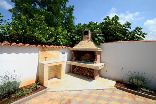 a outdoor pizza oven with a white wall at Apartments Villa Mimi in Višnjan