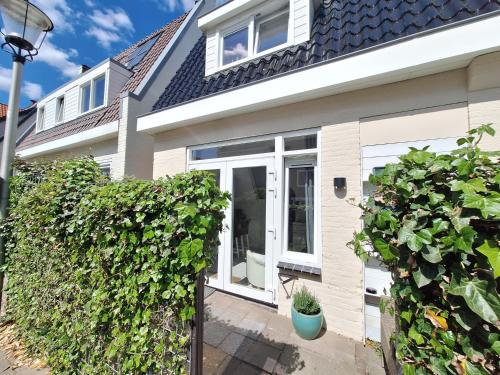 a house with white doors and a hedge at Huisje Louis in Zandvoort