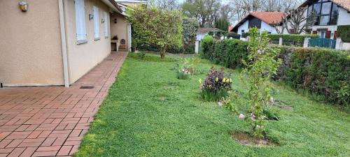 un jardin avec des fleurs dans l'herbe à côté d'une maison dans l'établissement 45Quiri, à Mont-de-Marsan